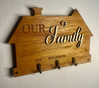Wooden plaque with 'Our Family' text and hooks on a white wall