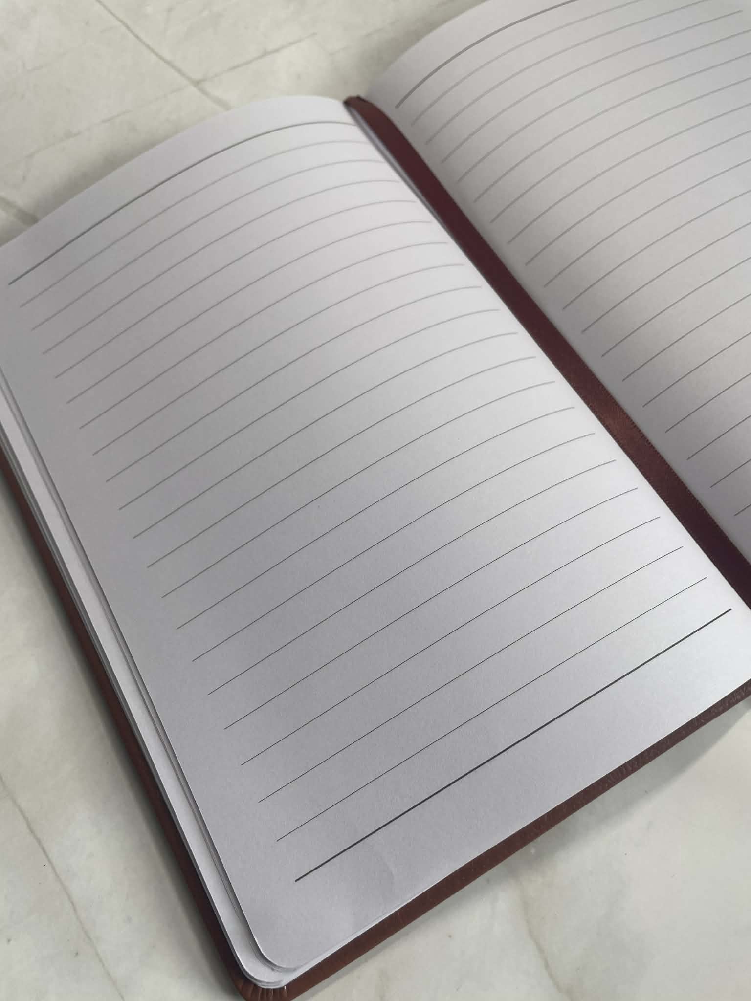 Open personalised notebook showing lined pages and ribbon bookmark, clean writing journal interior