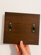 Back side of dog lead holder, showing dark wood stain with keyhole fixtures.
