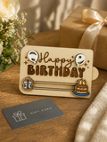Wooden happy birthday gift card holder displayed with wrapped gift box and card on table
