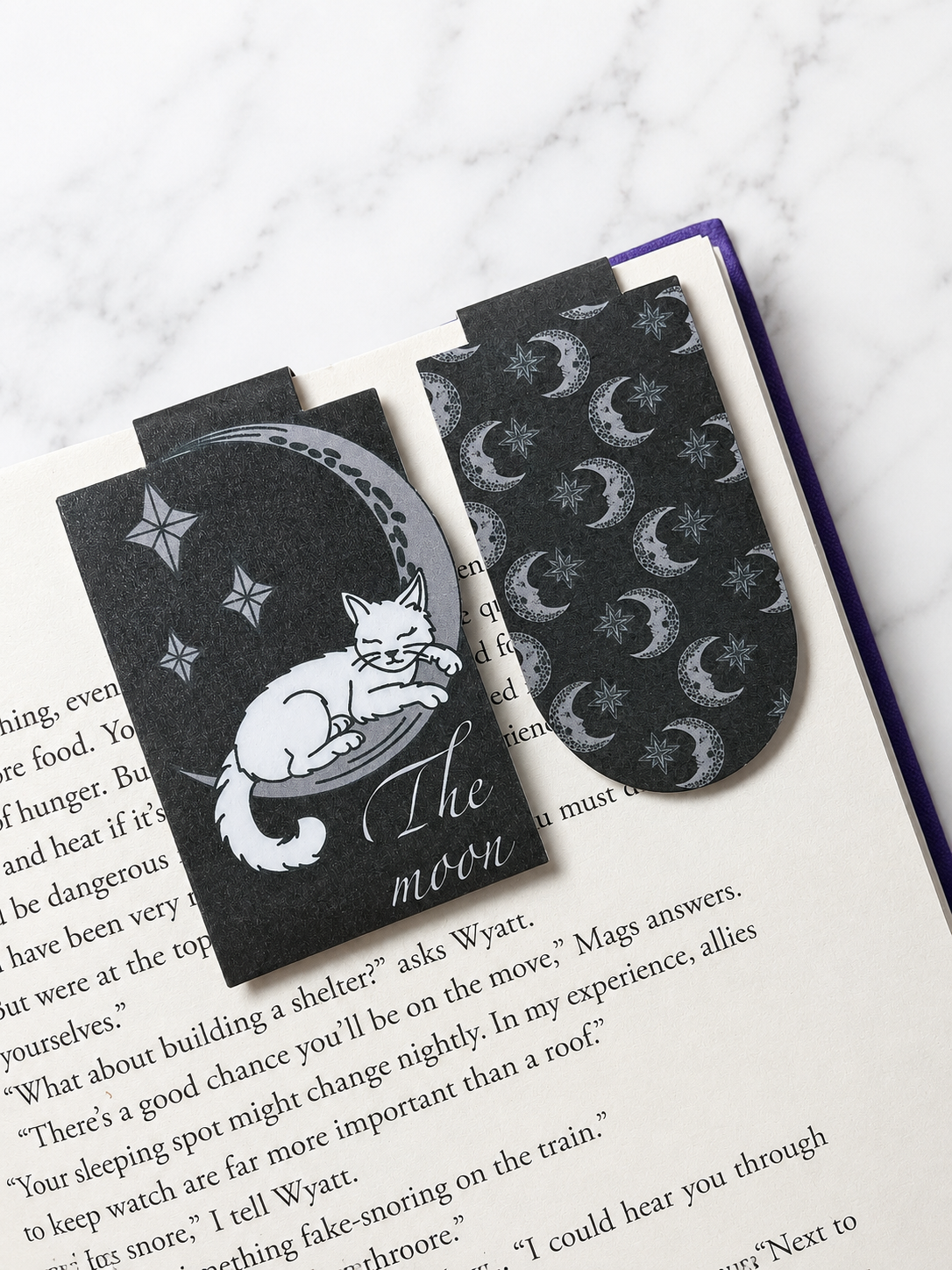 Moon cat magnetic bookmark and matching patterned bookmark placed inside an open book