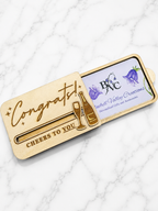 Close up of engraved champagne bottle and glass detail on wooden congratulations gift card holder