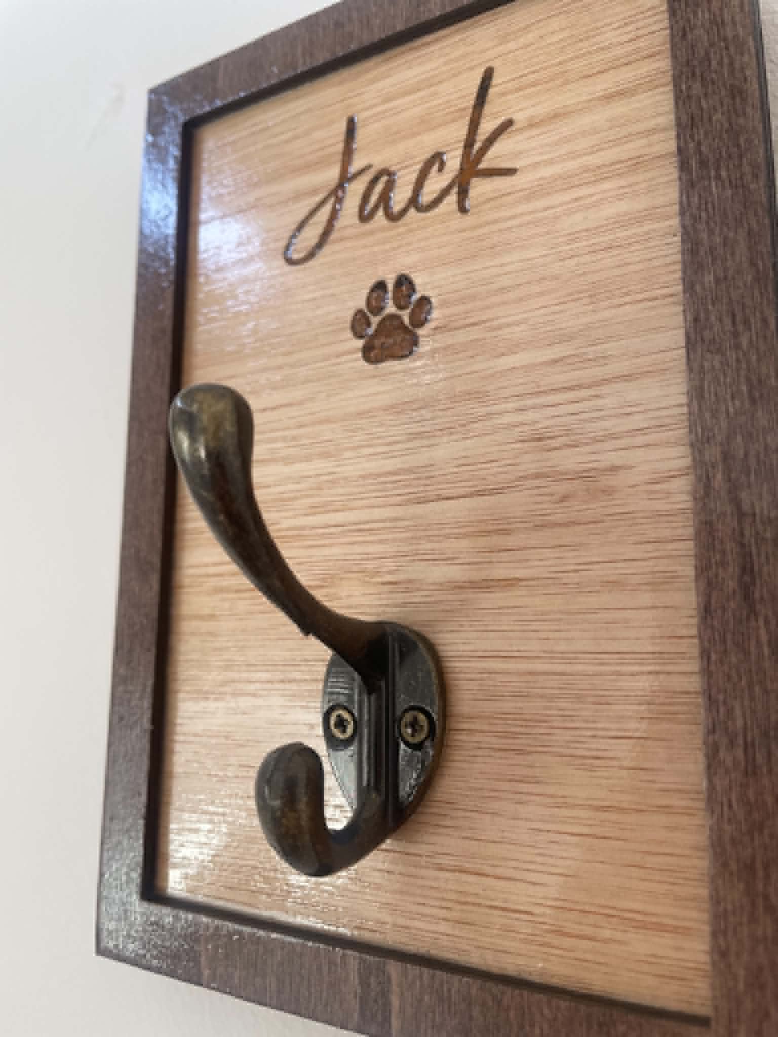 Wooden plaque with metal hook and engraved paw print, featuring the name 'Jack'.