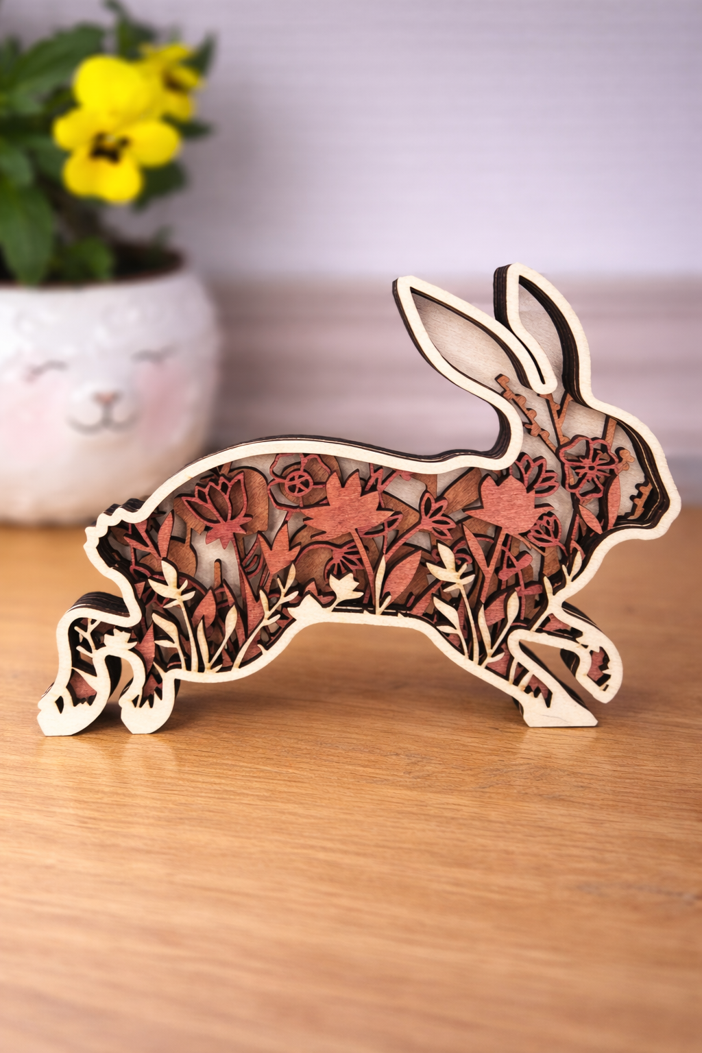Wooden rabbit decoration with pastel red florals layered within the silhouette.  