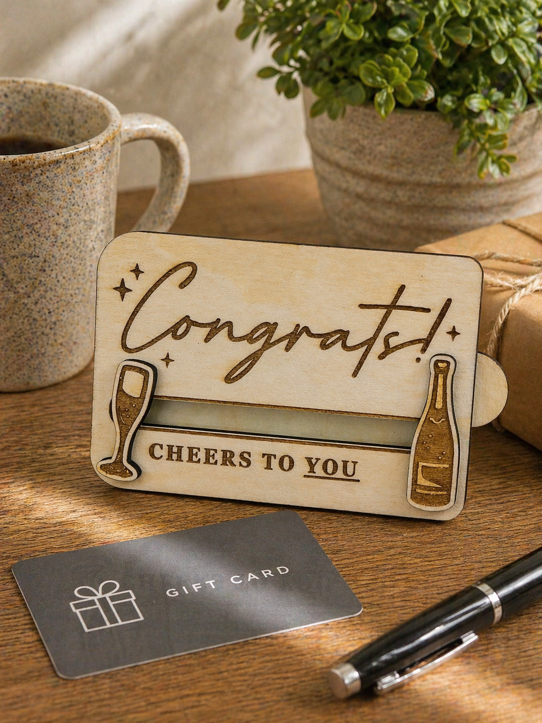 Wooden congratulations gift card holder displayed on desk with coffee mug and gift card