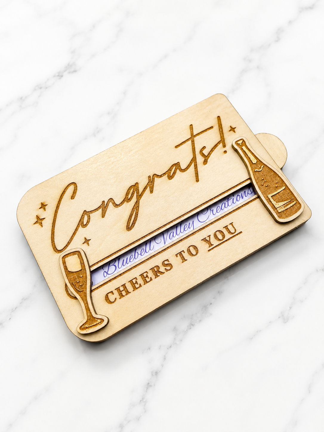 Wooden card with 'Congrats!' and 'Cheers to You' text on a marble surface