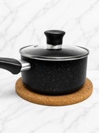 Black cooking pot placed on round cork trivet showing heat resistant kitchen use