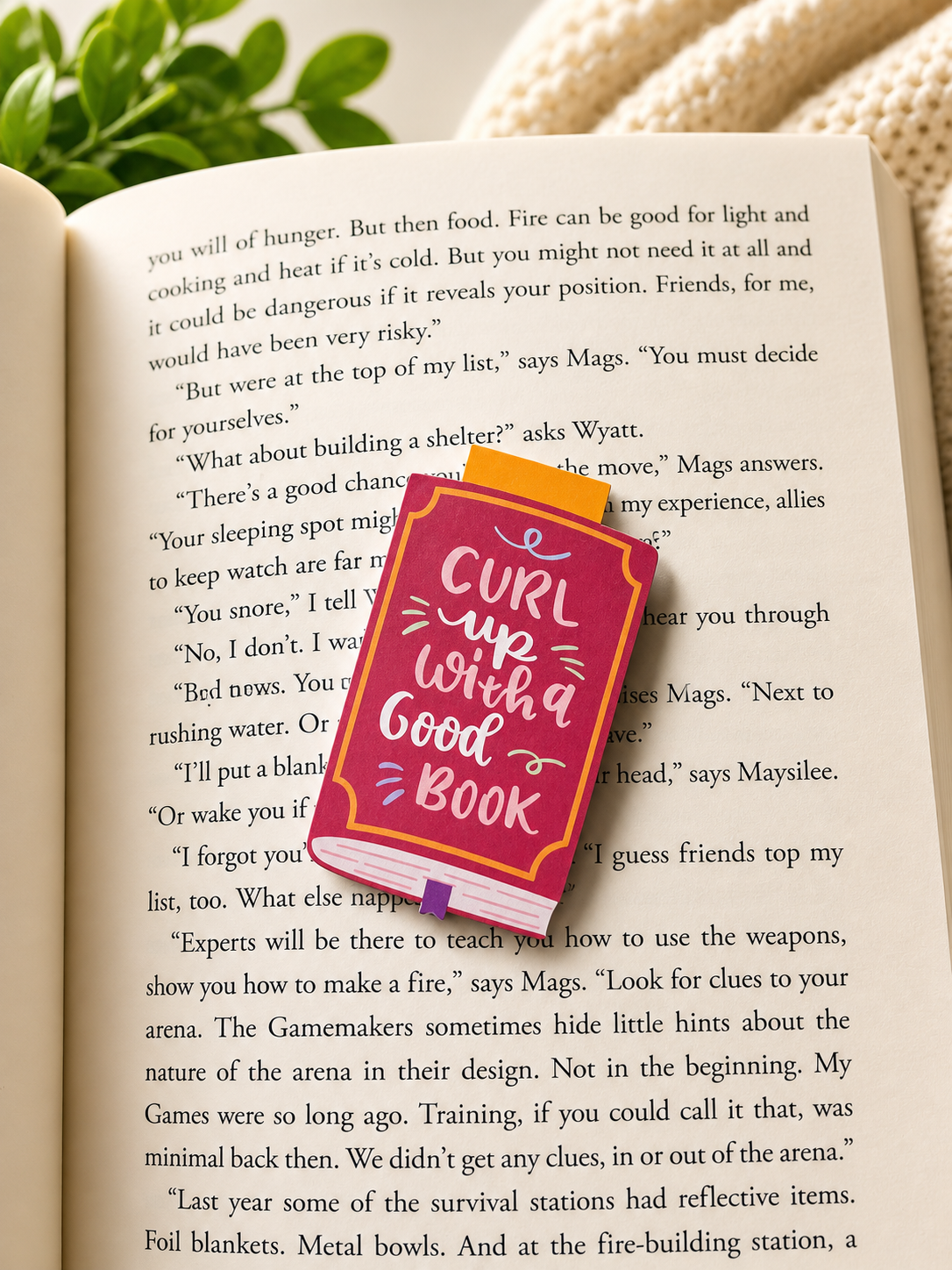 Magnetic bookmark on open book with warm cosy lighting and blanket background