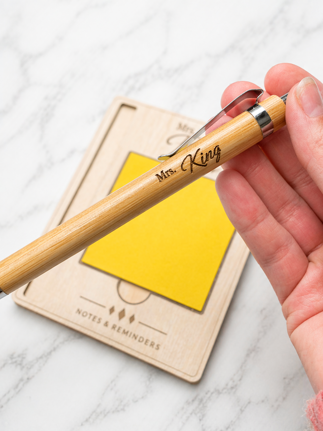 Close-up of personalised bamboo pen engraved Mrs King held in hand, custom name gift pen