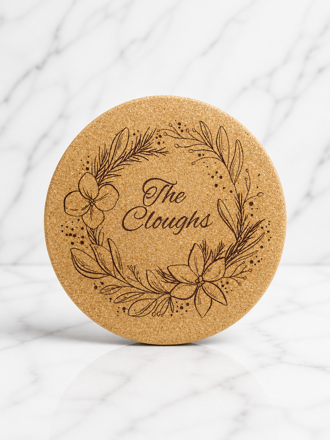 Round cork trivet engraved with floral wreath and personalised family name in centre