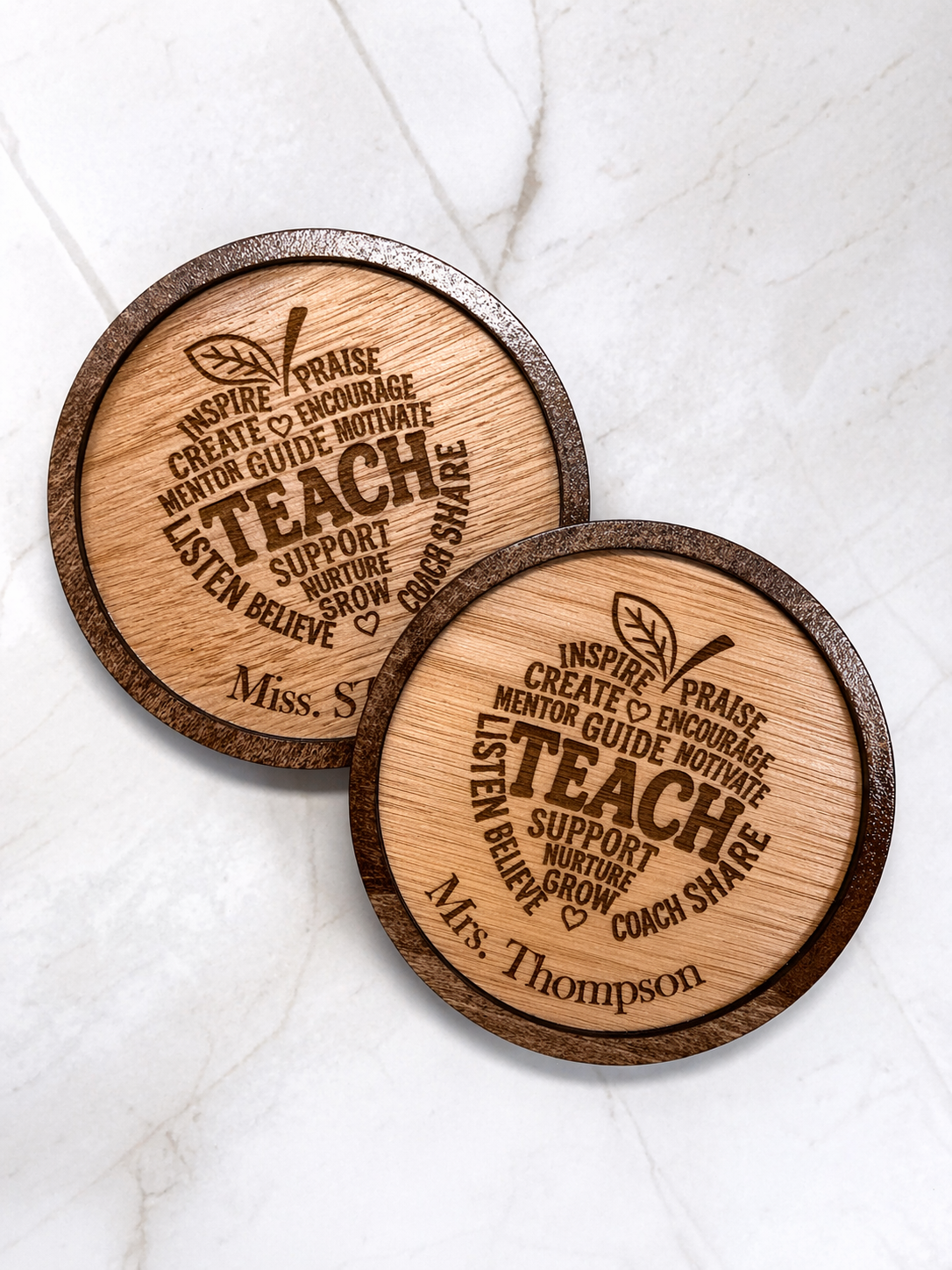Angled close up of two personalised wooden teacher coasters with engraved inspirational words and custom names