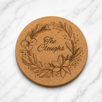 Round cork coaster with floral design and 'The Cloughs' text on a white surface