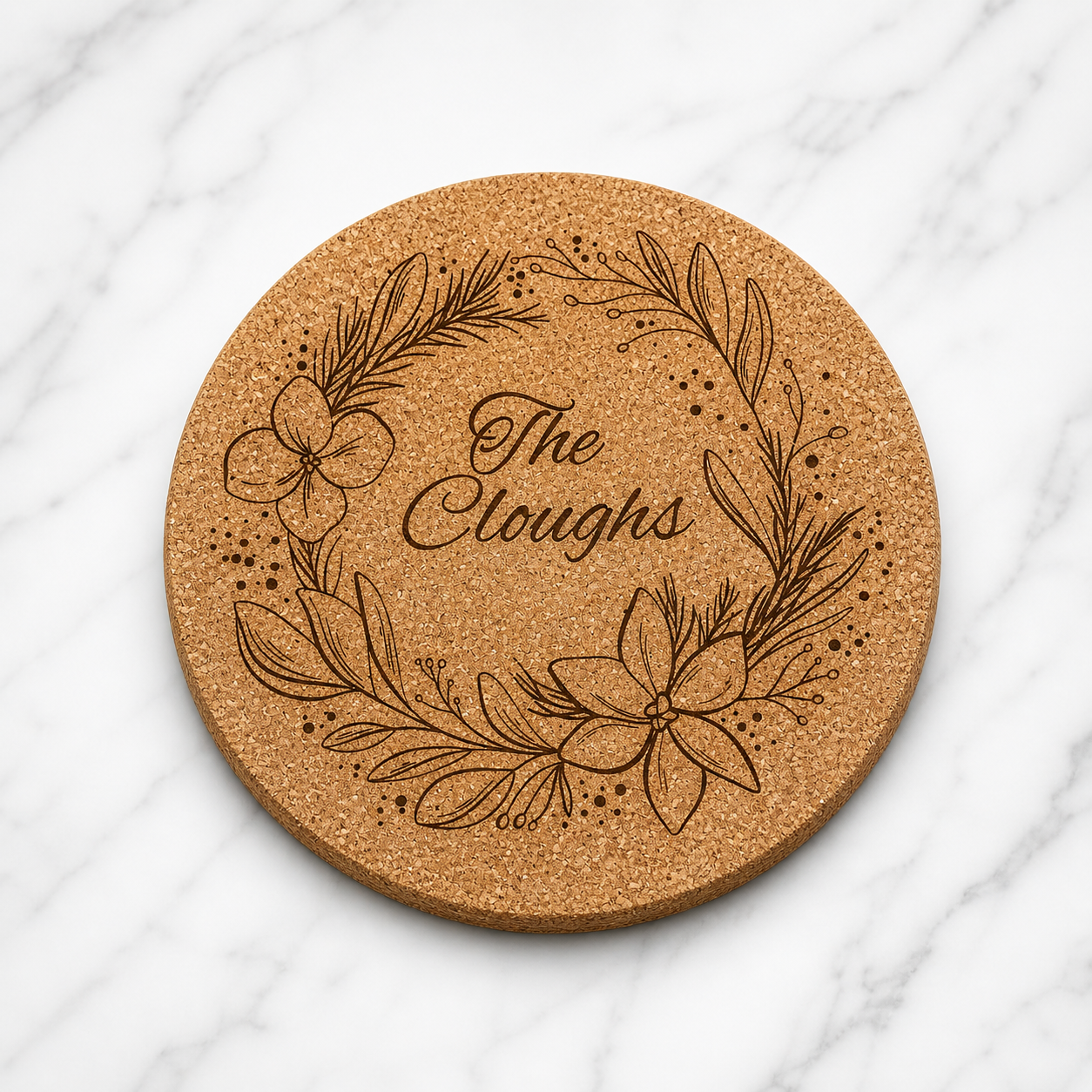 Round cork coaster with floral design and 'The Cloughs' text on a white surface