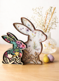 Decorative wooden bunny figures with floral patterns on the inside with wooden flower cutouts layered on top. There are 2 sizes and designs of pattern in the photo.