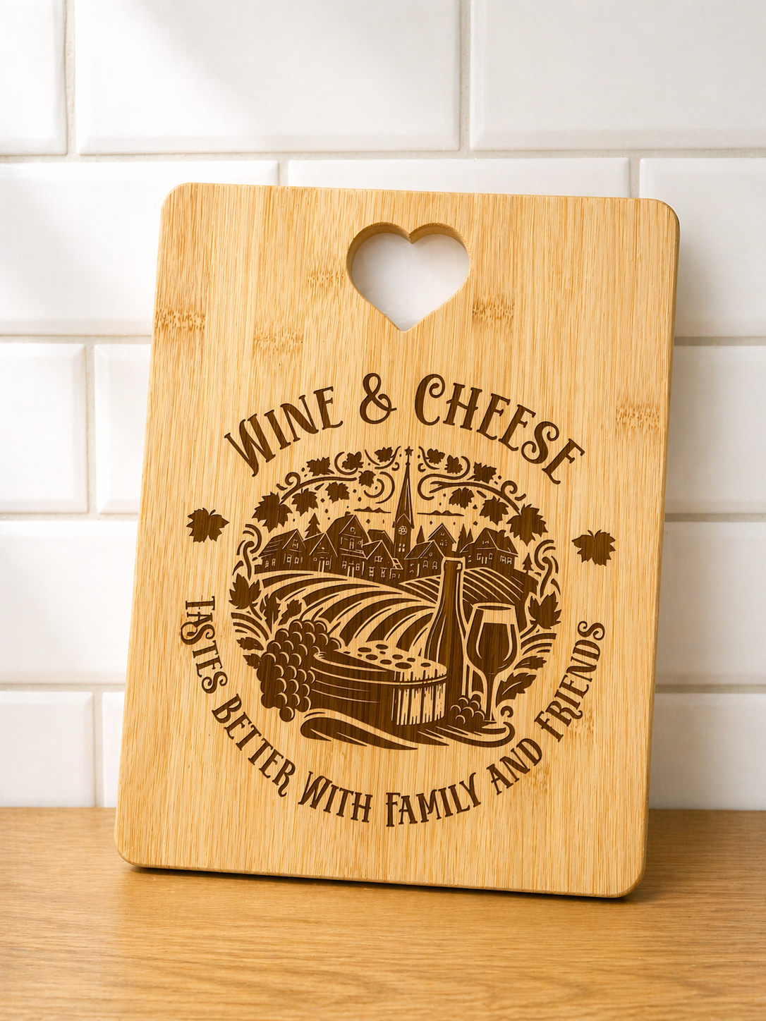 Rectangle bamboo cheese board engraved with wine and cheese design and heart handle displayed against tiled kitchen wall