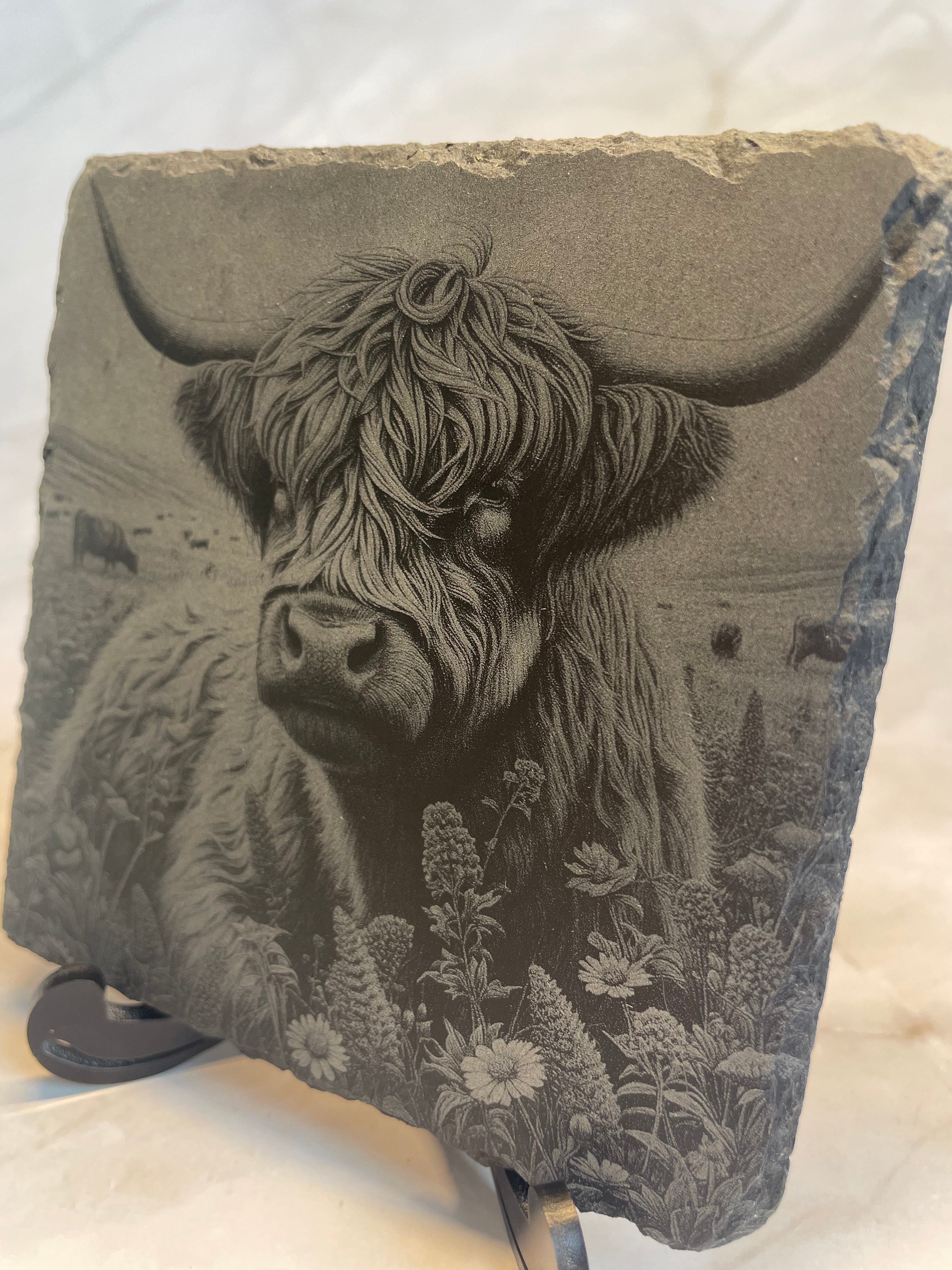 Decorative stone slate with engraved image of a Highland Cow and floral design on a white background