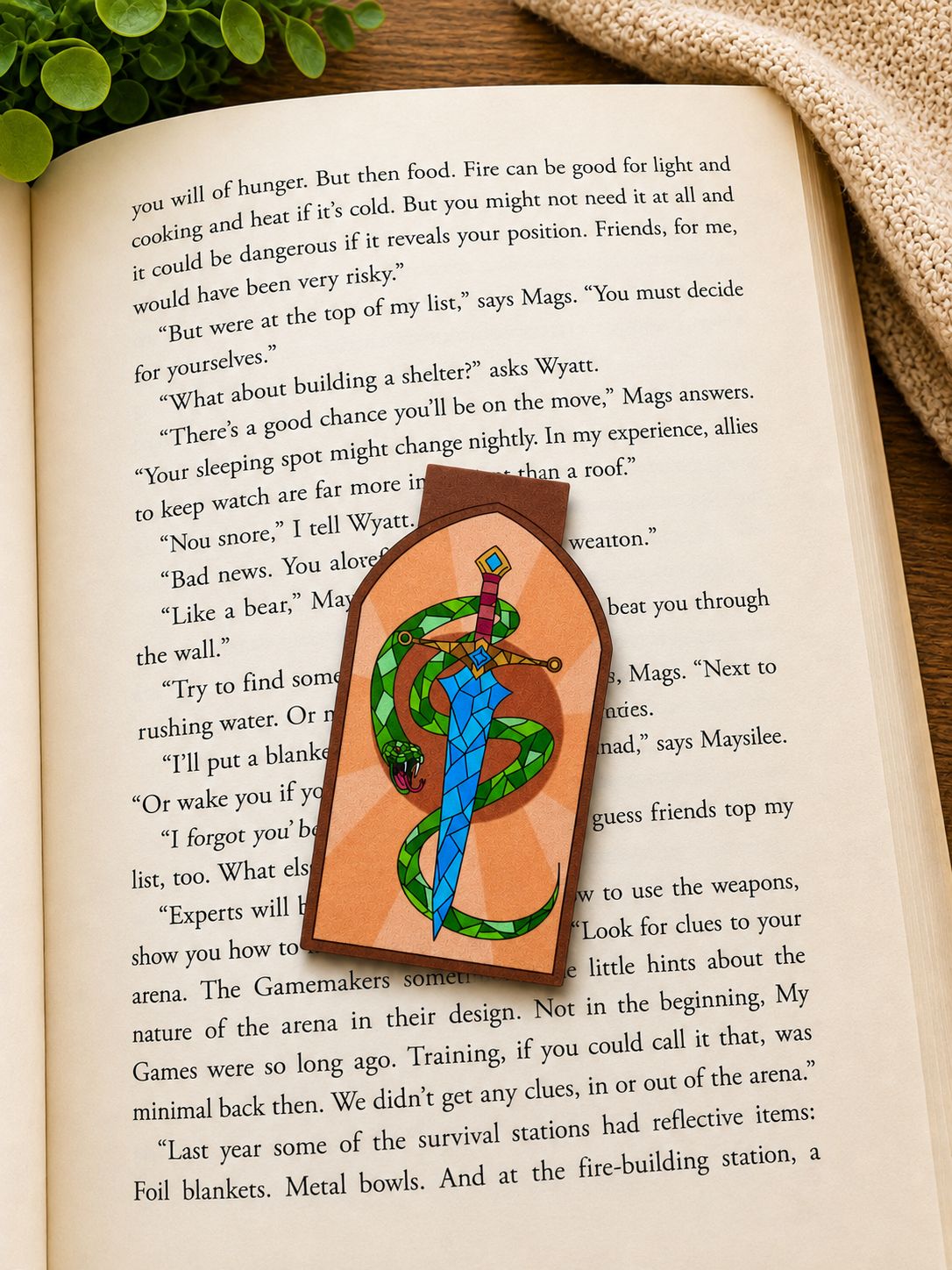 Magnetic bookmark with sword and snake design on an open book 