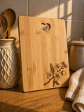 Bamboo chopping board with subtle floral engraving styled in warm kitchen setting with utensils and soft natural light