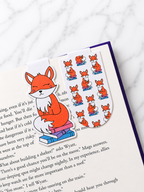 Two fox magnetic bookmarks clipped onto book pages showing both character and pattern designs in use