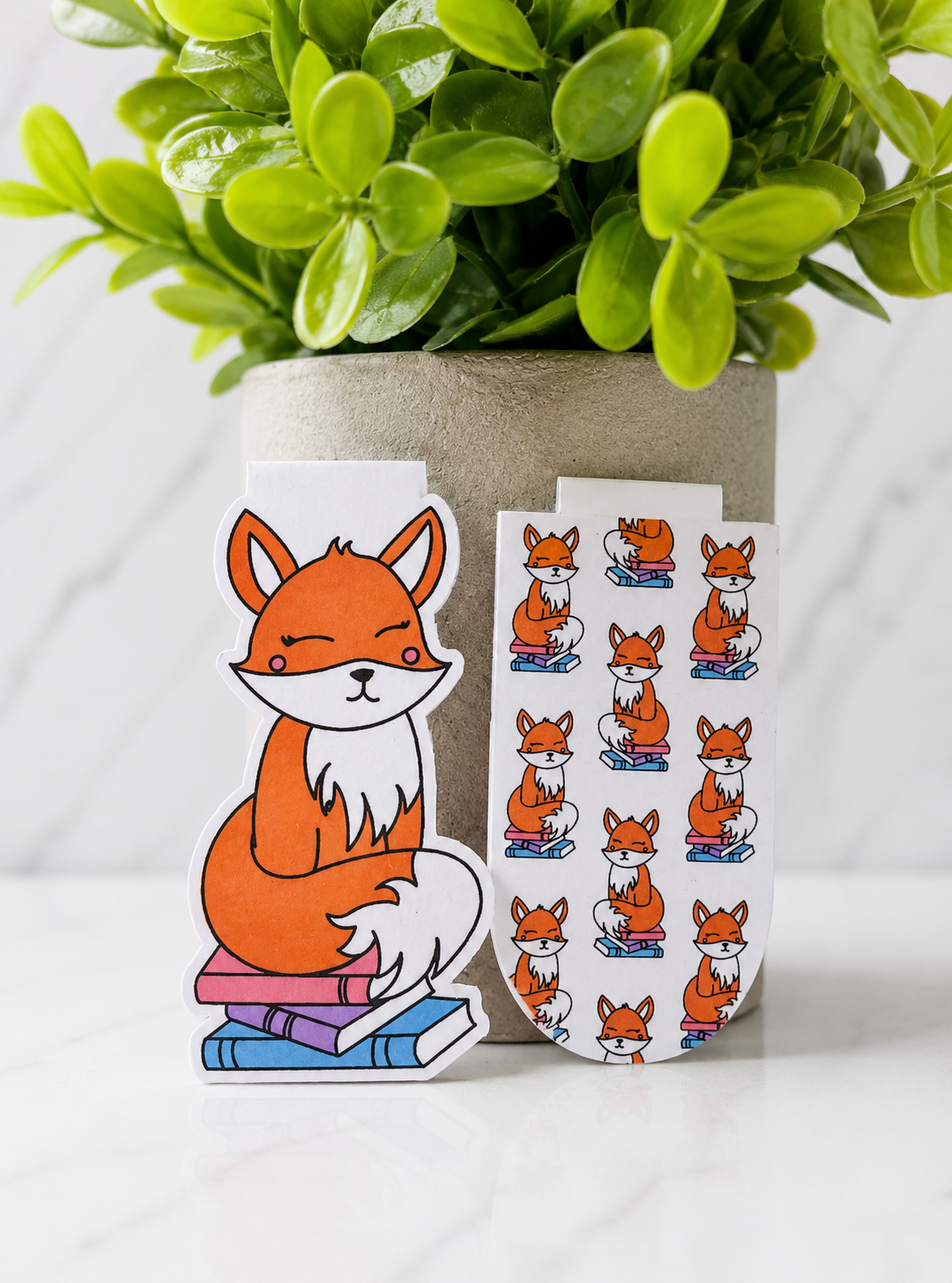 Two magnetic bookmarks featuring a fox on books and a matching fox pattern design displayed together