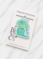 Cute frog magnetic bookmark attached to branded backing card packaging, showing how the bookmark is presented as a gift-ready item for readers and stationery lovers