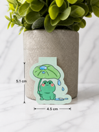 Small cute frog magnetic bookmark with a smiling green frog holding a leaf umbrella, shown against a neutral background with measurements displayed as approximately 5.1 cm tall and 4.5 cm wide