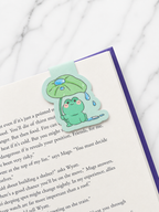 Small frog magnetic bookmark placed at the top of a book page, showing how the magnetic design grips both sides of the page to mark reading progress