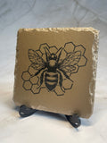 Gold painted slate with an engraved bee and honeycomb design.