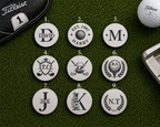 Nine personalised golf ball markers on a green surface with golf equipment.