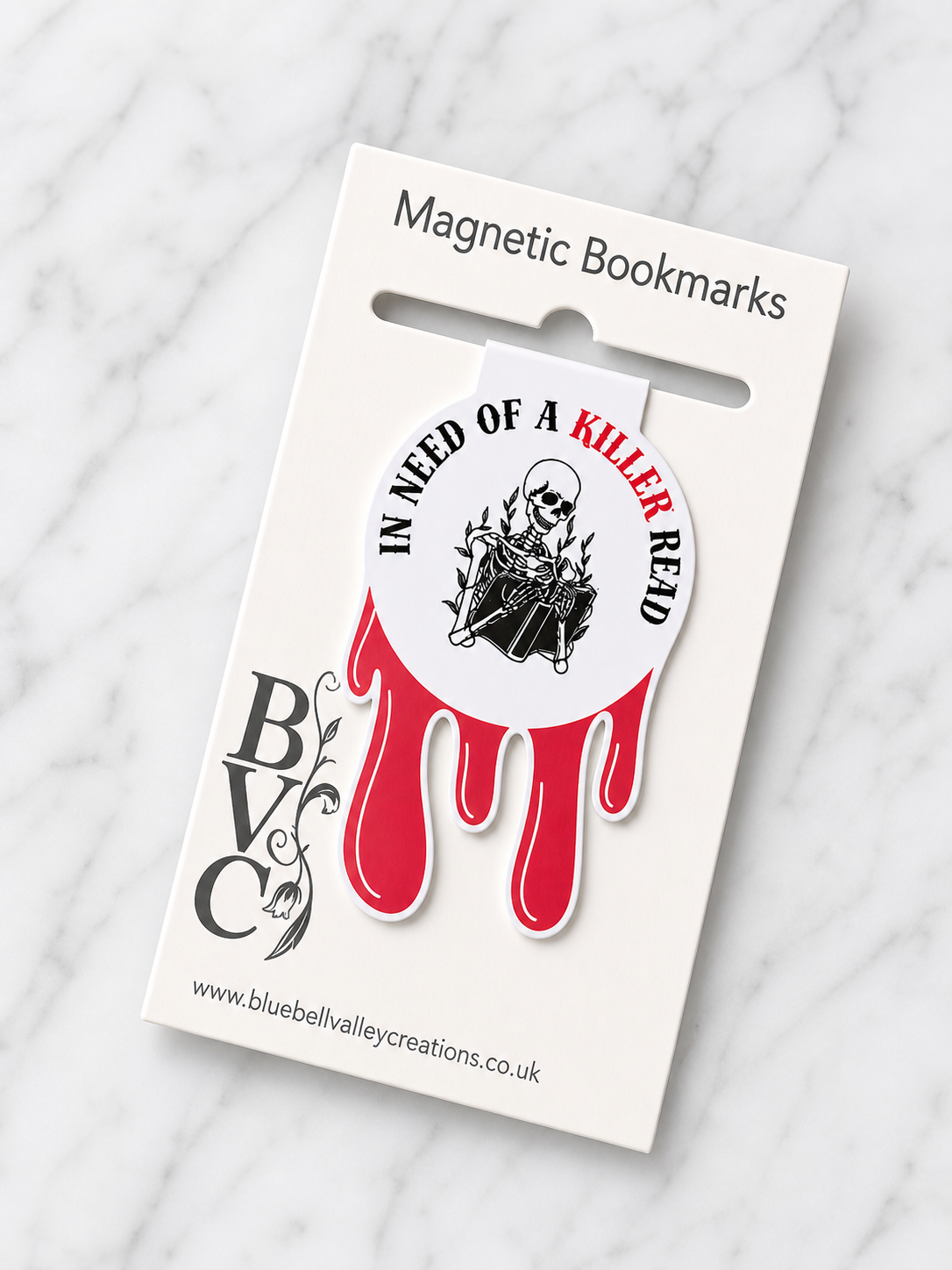 Skeleton themed magnetic bookmark with red drip design attached to Bluebell Valley Creations branded packaging card, showing retail presentation on marble background