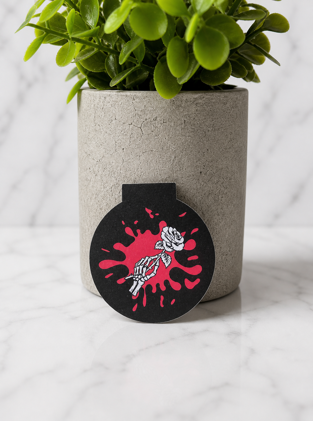 Black magnetic bookmark with skeleton hand holding rose and red splash background