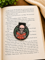 Skeleton reading magnetic bookmark placed on an open book in a cosy reading setting with warm tones