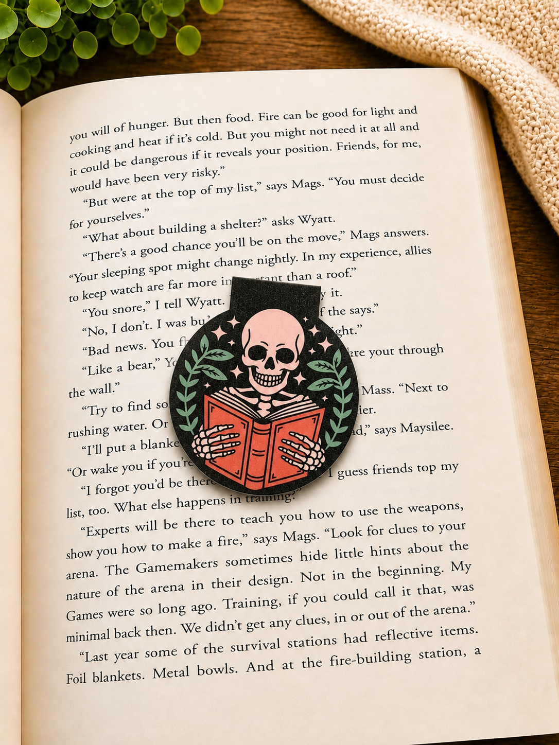 Skeleton reading magnetic bookmark placed on an open book in a cosy reading setting with warm tones