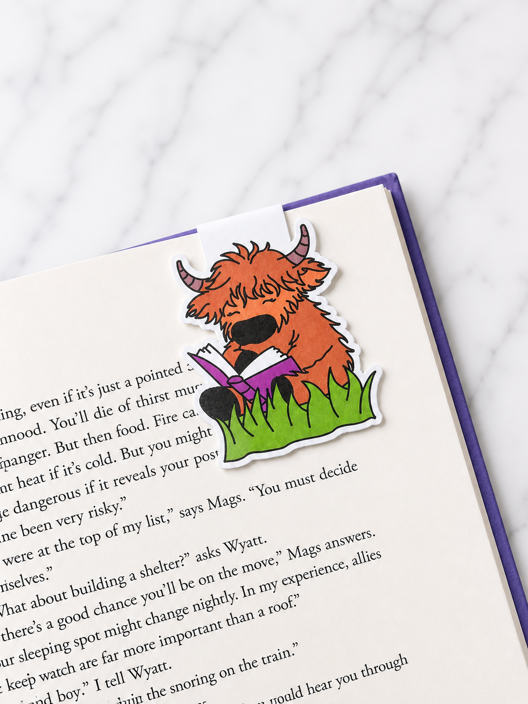 Highland cow magnetic bookmark clipped onto a book page demonstrating practical use and secure page marking