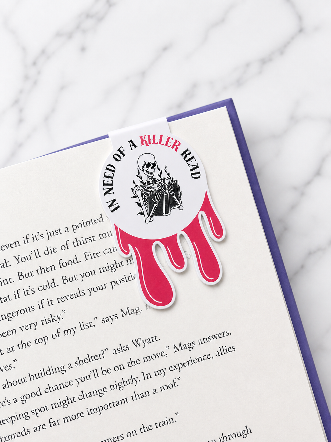 Gothic style magnetic bookmark with skeleton reading illustration clipped onto the top of an open book page, demonstrating how it securely holds pages while reading