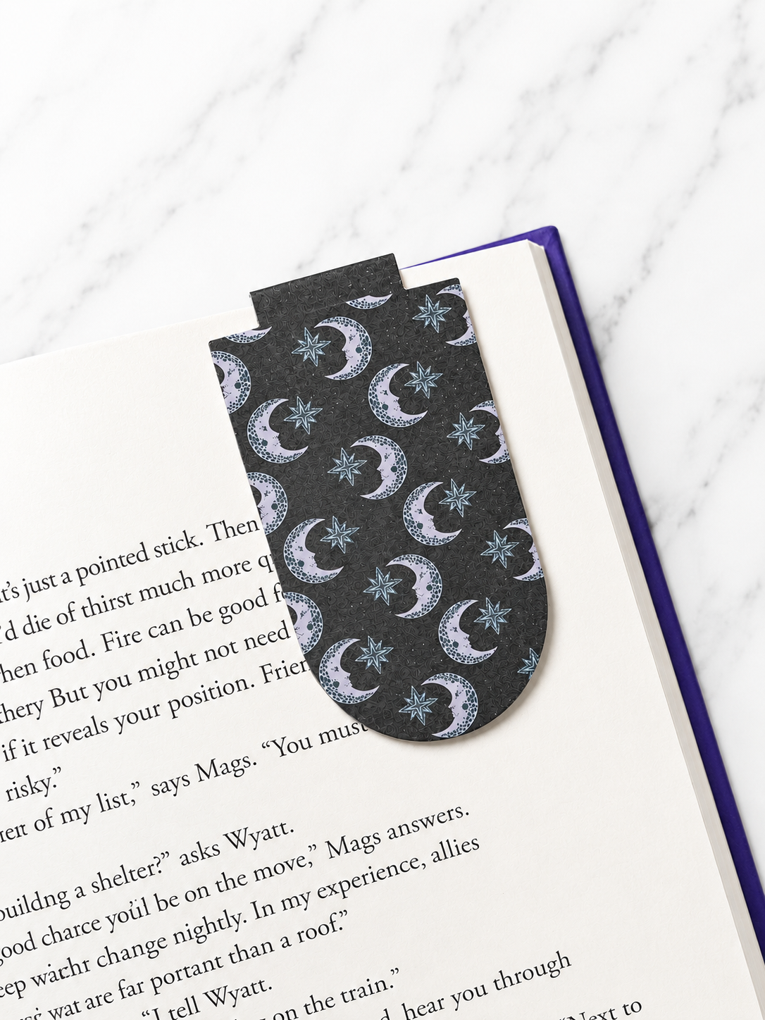 Magnetic bookmark with moon and star pattern clipped onto a book page
