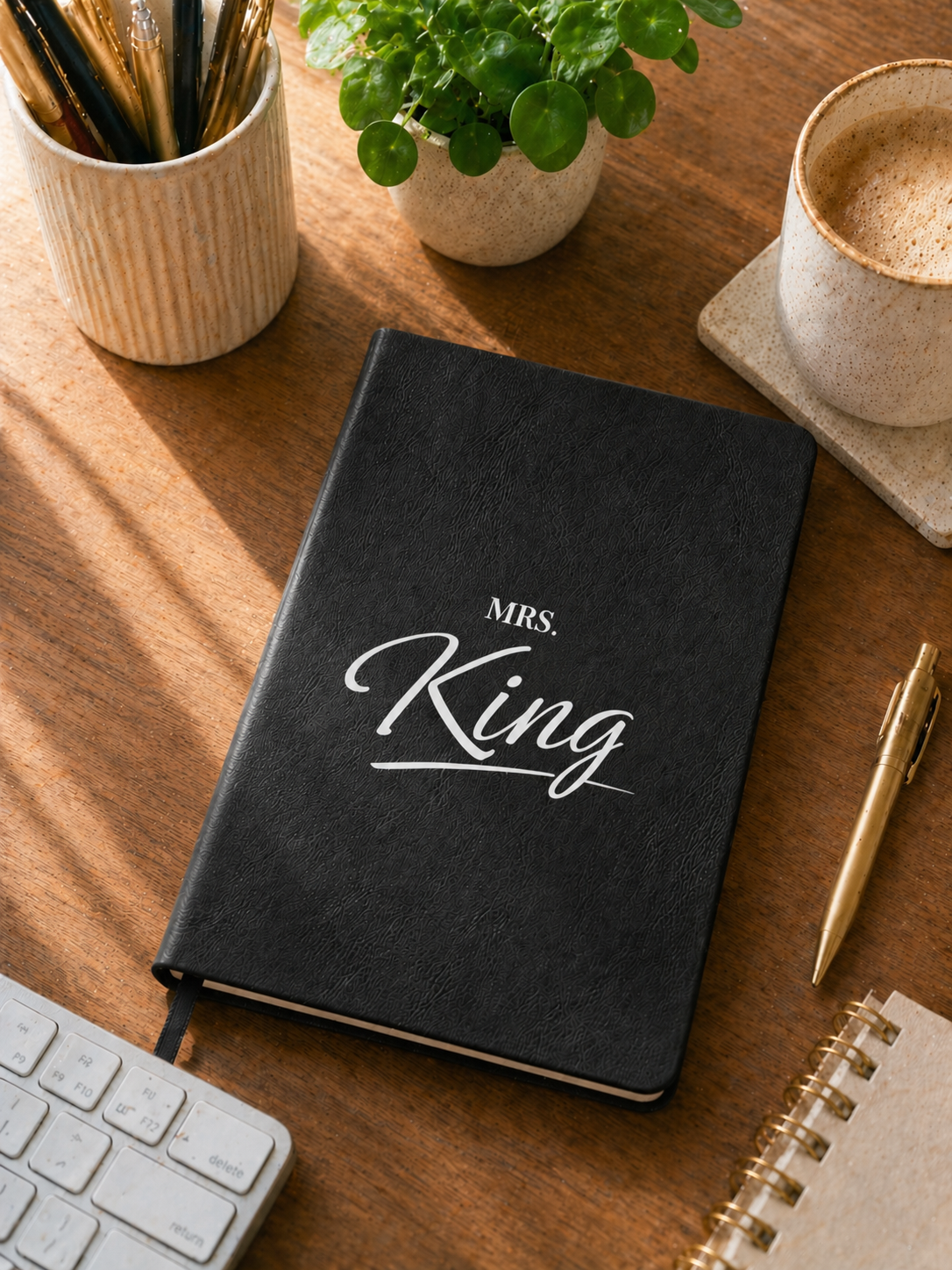 Black notebook with 'Mrs. King' on a wooden desk with office supplies