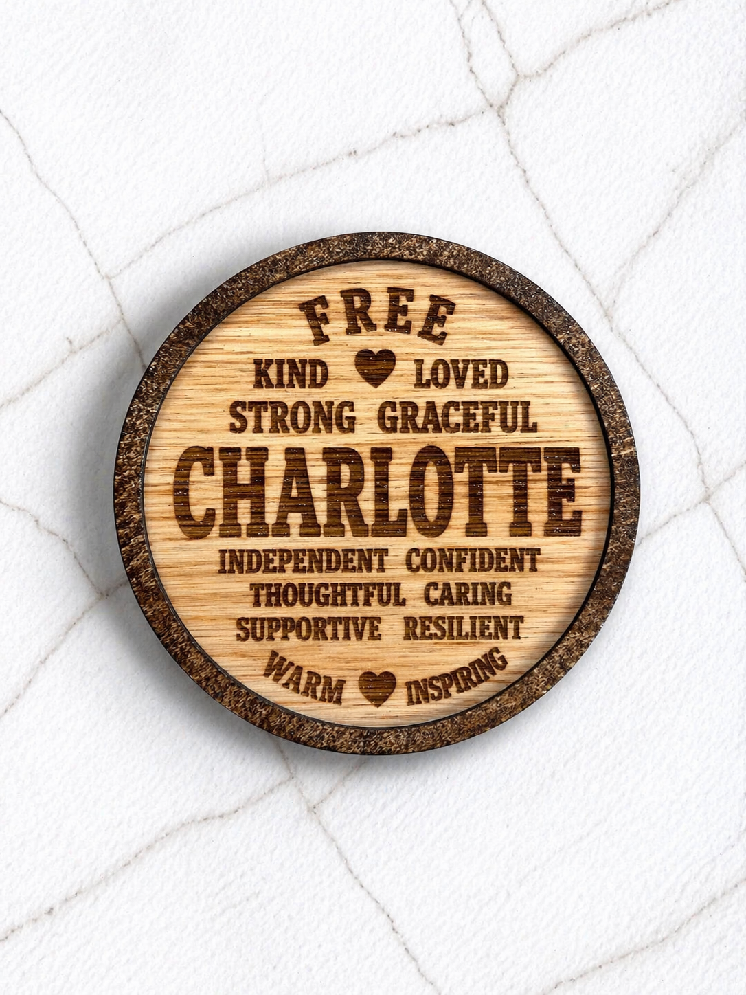 Wooden engraved coaster featuring the name Charlotte and positive traits, personalised gift idea displayed on marble