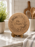 Engraved cork trivet displayed in bright kitchen setting with utensils and plants