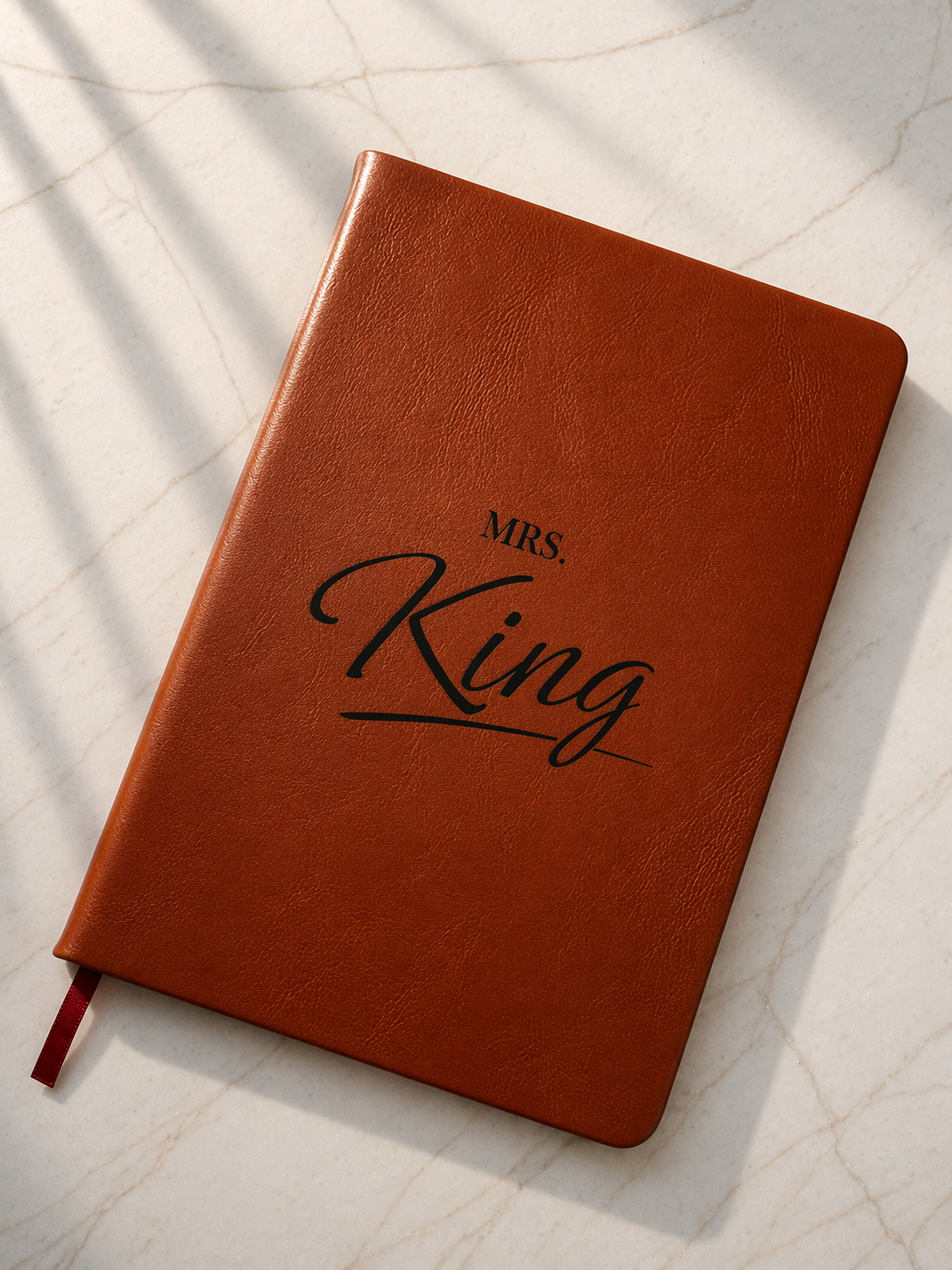 Personalised brown leather notebook engraved the name: Mrs. King on light marble background 