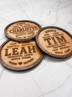Three personalised engraved wooden coasters with different names and positive words arranged neatly on marble surface