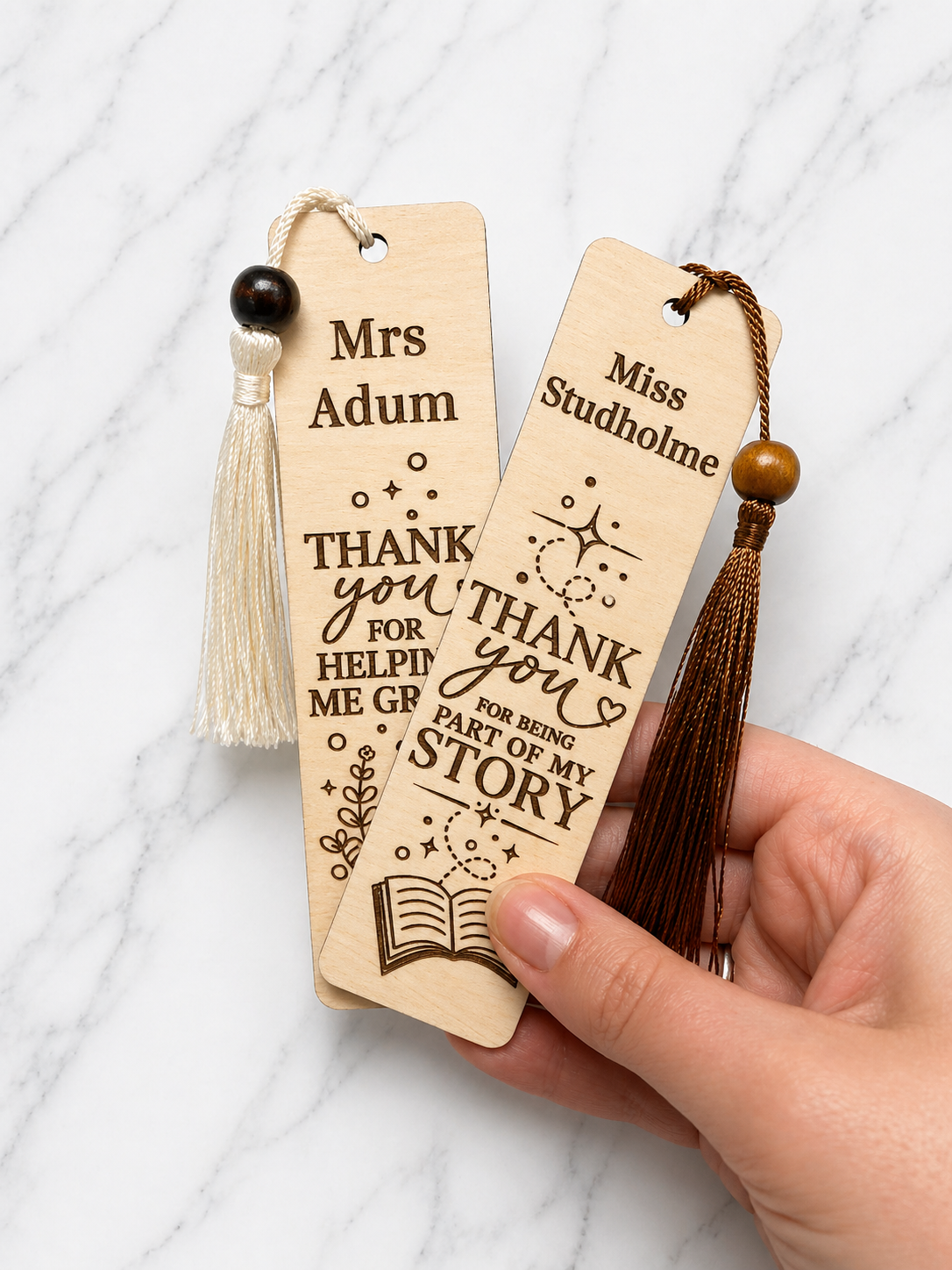 Personalised teacher bookmarks with tassels held in hand showing engraved thank you designs