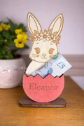 Wooden rabbit money holder with a cracked egg and money, name engraved on the stained red egg.