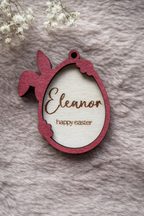 Wooden Easter tag with a bunny holding an egg. the outline is stained red mahogany. Written inside the egg are 'Eleanor' and 'Happy Easter'.
