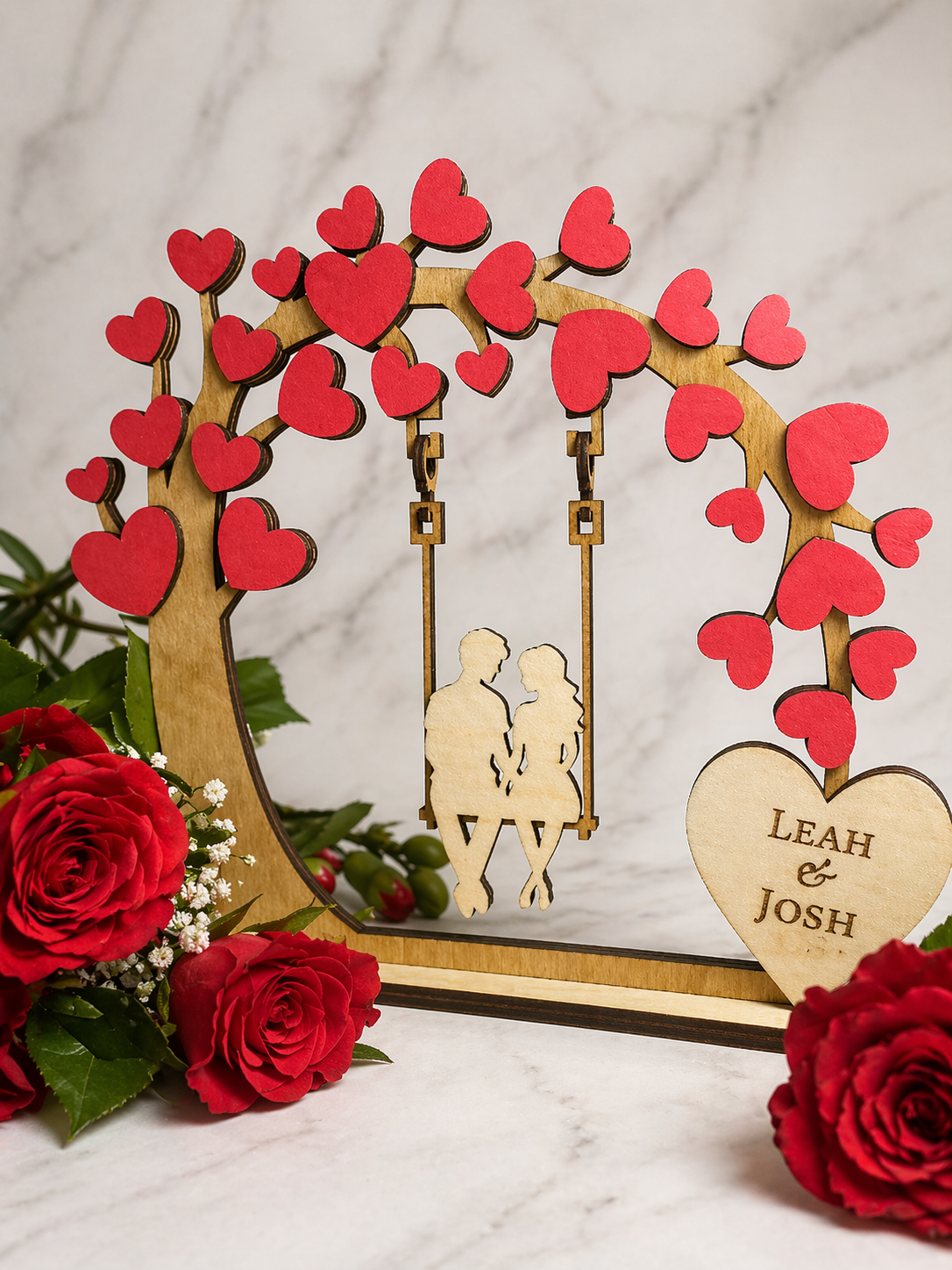 Personalised couple tree swing ornament displayed with red roses for romantic gift setting