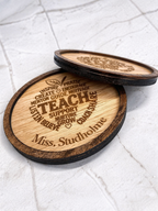 Two engraved wooden teacher coasters stacked showing detailed engraving and layered wood design on marble surface