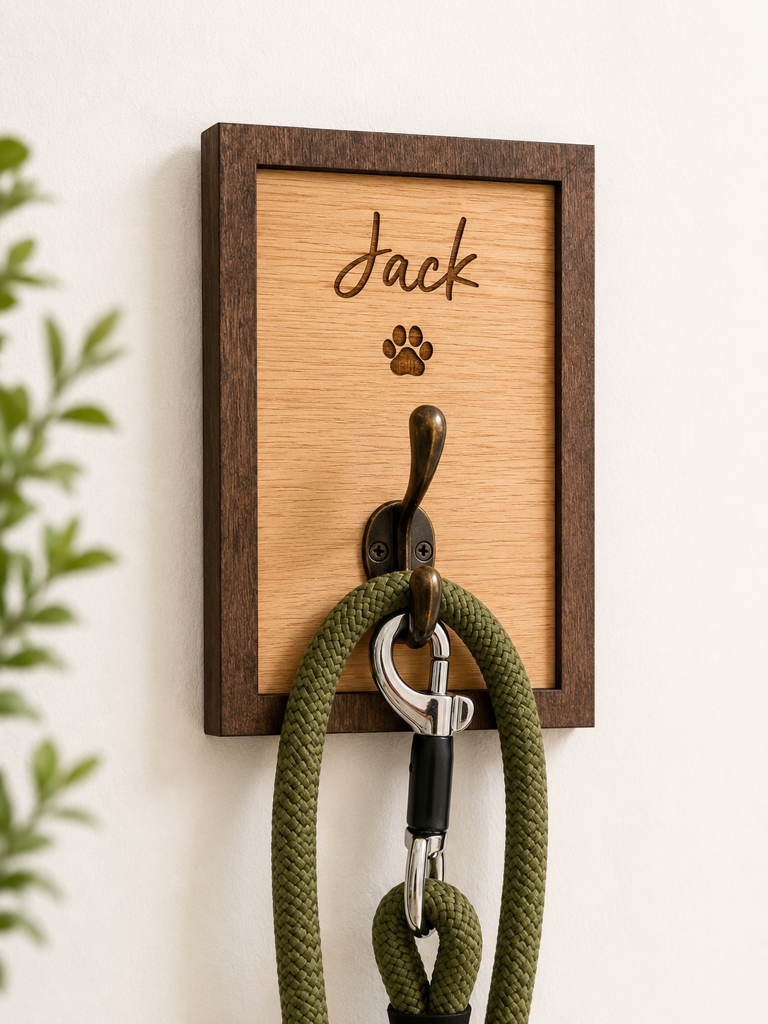 Wooden wall hook with engraved name 'Jack' and a green dog leash attached, on a light background.