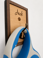 Wall-mounted wooden plaque with 'Jack' and a paw print, attached to a white wall with a blue and grey lead.