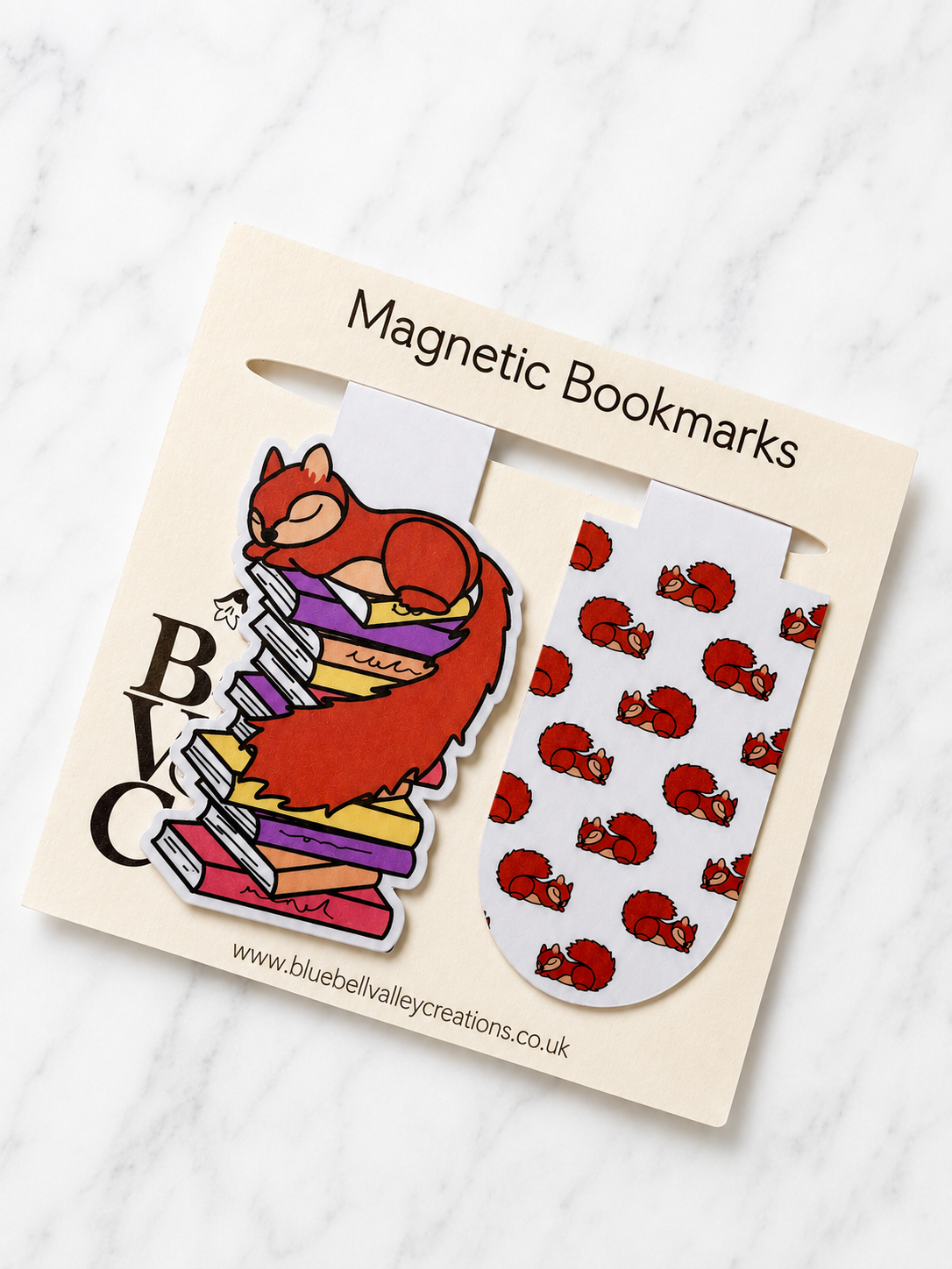 Set of magnetic bookmarks featuring a sleeping squirrel on a stack of books and matching squirrel pattern on branded packaging