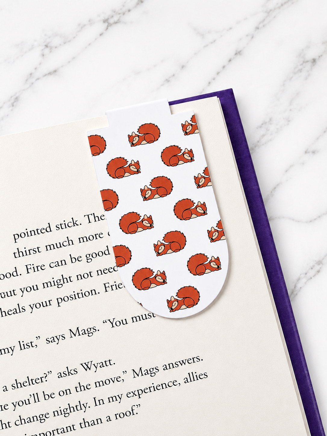 Magnetic bookmark with sleeping squirrel pattern clipped onto a book page showing how it holds place securely